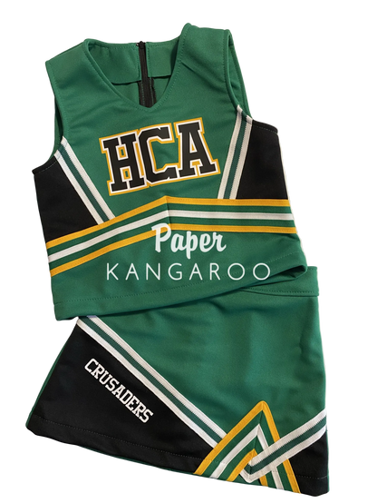 A green and black cheerleader uniform set with white, yellow, and green stripes, featuring 'HCA' on the top and 'CRUSADERS' on the skirt, laid flat on a white surface.