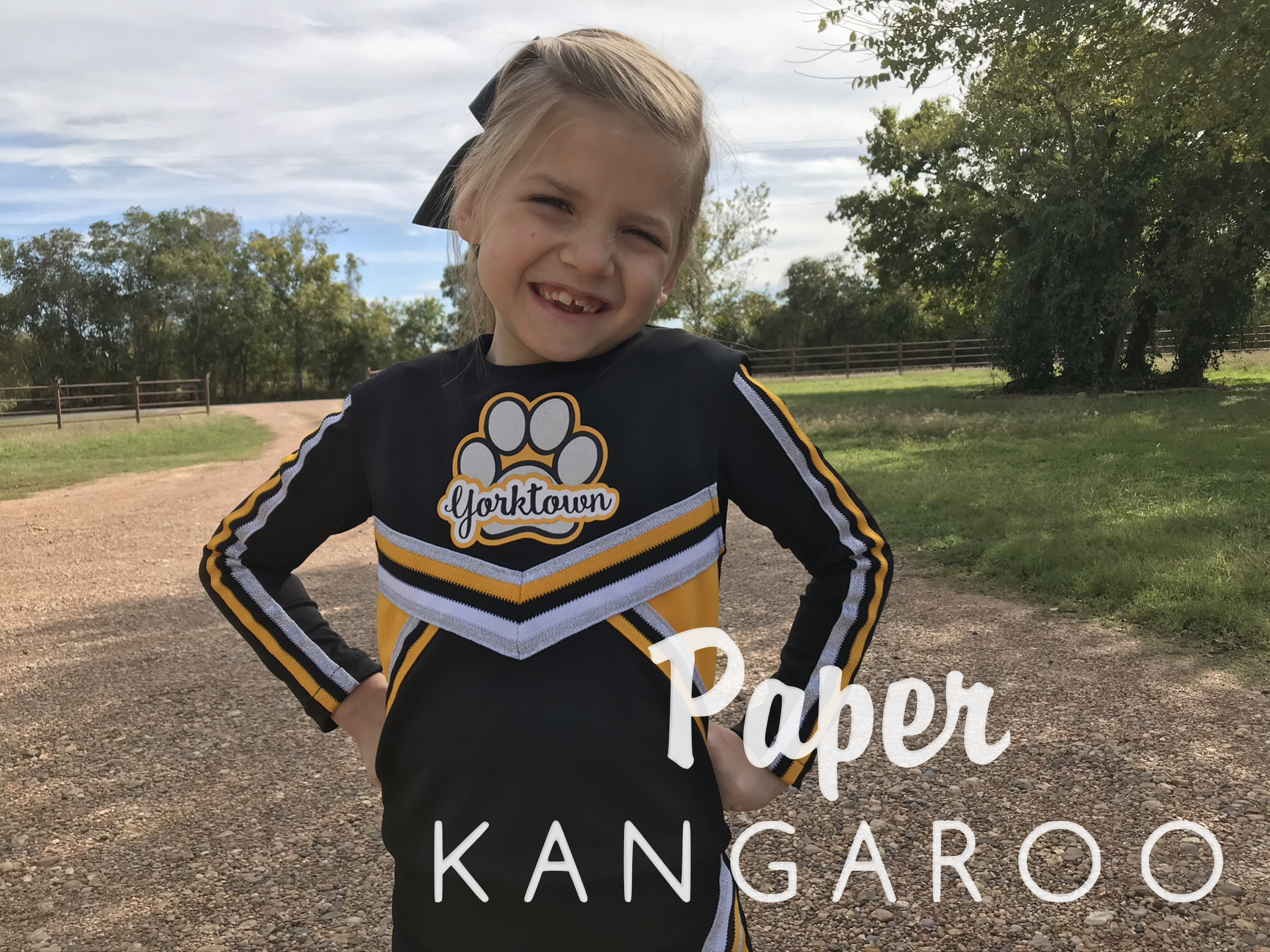 black white and athletic gold cheer uniform and sleeves on a young girl. A pawprint with Yorktown is written across the chest. Paper Kangaroo