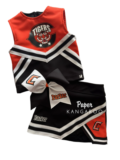 A two-piece toddler cheerleader outfit set featuring a sleeveless top and matching shorts in red, black, and white, with a large white bow. The top displays 'Tigers' and a tiger graphic, while the shorts feature 'Parker' and a letter 'C'.